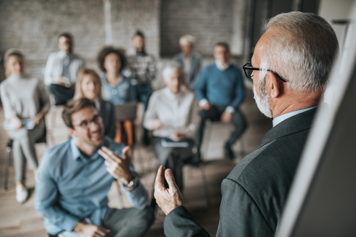 Senior manager talking to large group of his colleagues on a business seminar.